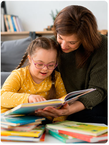 Niña con síndrome de Down leyendo un libro junto a su madre en casa