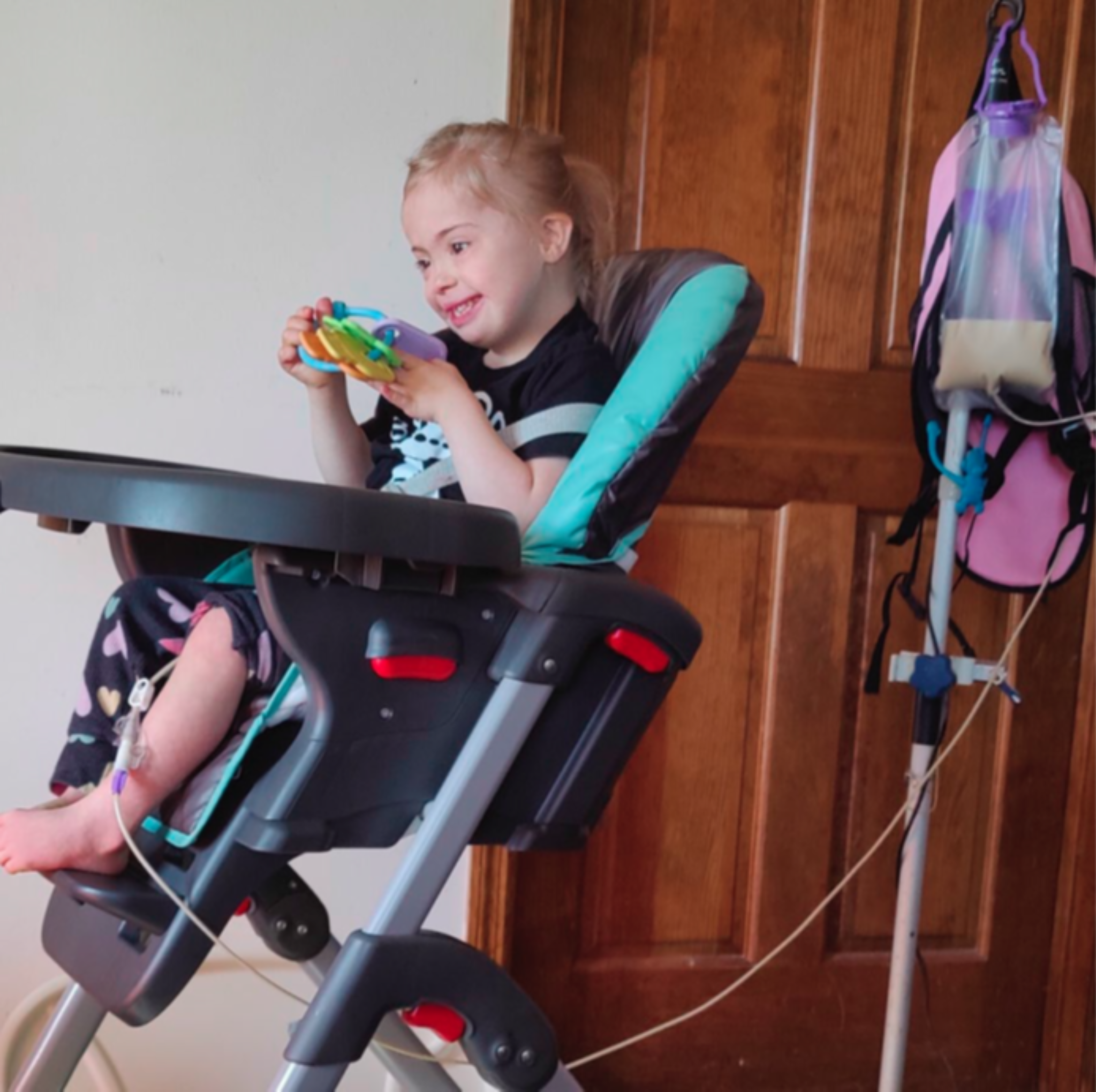 Comida familiar en la que una niña con síndrome de Down recibe alimentación por sonda sentada en su silla alta